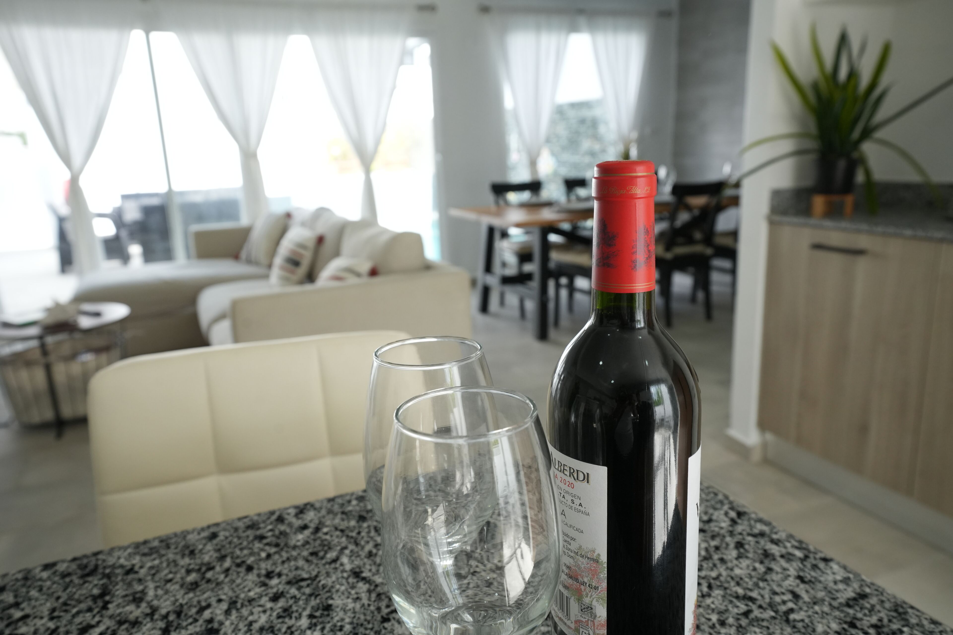 A dining area with a table, two wine glasses, and a bottle of wine.