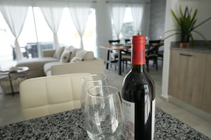 A dining area with a table, two wine glasses, and a bottle of wine.