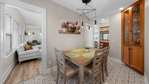 A dining area with a wooden table, chairs, a ceiling light fixture, and a kitchen area with cabinets. - Mission Hills retreat, walkable, free parking (San Diego)