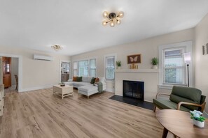 A spacious living room with a fireplace, a dining area, and a kitchen in the background. - Mission Hills retreat, walkable, free parking (San Diego)