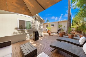 Eine Terrassenfläche mit Gartenmöbeln, einem Heizstrahler und Topfpflanzen.