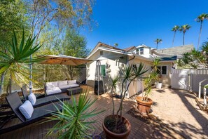 Ein Patio-Bereich mit einer Couch, Blumentöpfen und einer Pergola.