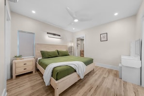 Ein Schlafzimmer mit Bett, Nachttisch, Schreibtisch und Deckenventilator.