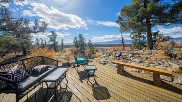 A wooden deck with a sofa, chairs, and a bench, overlooking a mountainous landscape. - Ridgeview Haven-perfect retreat (Fairplay)