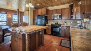 A kitchen with wooden cabinets, a central island, a refrigerator, a stove, and a microwave. - Ridgeview Haven-perfect retreat (Fairplay)