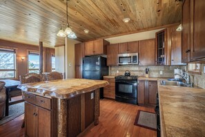 A kitchen with wooden cabinets, a central island, a refrigerator, a stove, and a microwave. - Ridgeview Haven-perfect retreat (Fairplay)