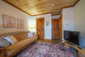 Ein Wohnzimmer mit einer Couch, einem Fernseher und einem gemusterten Teppich.