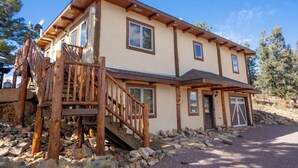 A two-story house with a wooden staircase, stone foundation, and a garage. - Ridgeview Haven-perfect retreat (Fairplay)