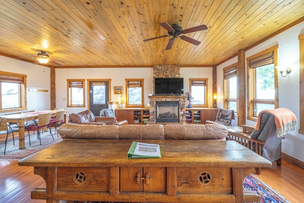 Ein geräumiges Wohnzimmer mit Holzboden, Kamin und Fernseher.