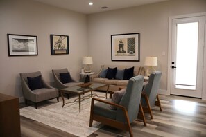 A living room with a sofa, two armchairs, a coffee table, and two lamps. There are framed pictures on the wall. - Stylish 4BR Near Hobby, Med Center, NRG & Downtown (Houston)
