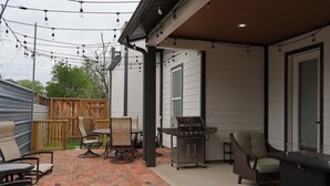 A patio area with a grill, chairs, and a table. - Stylish 4BR Near Hobby, Med Center, NRG & Downtown (Houston)