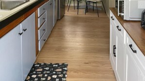 Una cocina con armarios de madera, un refrigerador, una mesa de comedor con sillas y una ventana con vistas.