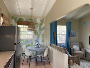 A kitchen with a refrigerator, dining table with chairs, and a wall with leaf patterns. - A stylish 3-bdrm coastal-inspired retreat overlooking Grand Anse Beach. (Saint George)