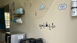 Una cocina con tostadora, cafetera y un adorno de pez en la pared.