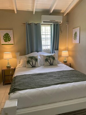 Una camera da letto con un letto, due abat-jour, una finestra con tende e opere d'arte alle pareti.
