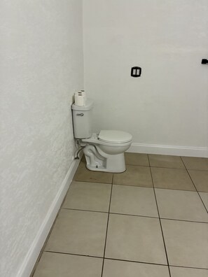 Un bagno con il water, pareti bianche e pavimento piastrellato in beige.