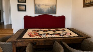 A dining area with a wooden table, red upholstered headboard, and wicker chairs. - 200 Acre Retreat, Family Friendly, Stargazing, More (Hesperus)