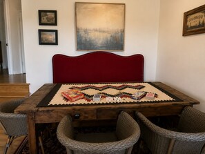 A dining area with a wooden table, red upholstered headboard, and wicker chairs. - 200 Acre Retreat, Family Friendly, Stargazing, More (Hesperus)