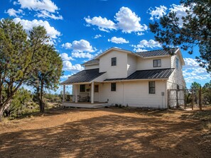 A two-story house with a porch, a fenced yard, and a clear sky. - 200 Acre Retreat, Family Friendly, Stargazing, More (Hesperus)