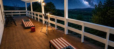 A covered outdoor deck with a telescope, benches, and a starry night view.