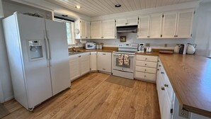 A kitchen with white cabinetry, a refrigerator, a microwave, an oven, and a wooden countertop. - 200 Acre Retreat, Family Friendly, Stargazing, More (Hesperus)