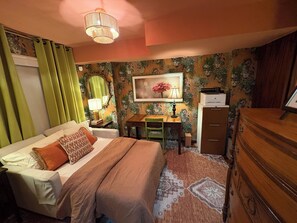 A bedroom with a bed, desk, chair, dresser, and a wall with floral wallpaper. - Toronto East Convenient Professionally Decorated Urban Oasis (Toronto)