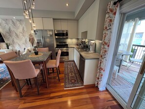 A modern kitchen with a dining area, wooden flooring, and a view to the outside. - Toronto East Convenient Professionally Decorated Urban Oasis (Toronto)