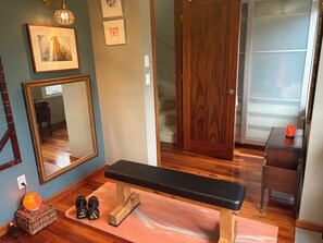 A room with a wooden bench, a mirror, a small table with a lamp, and a pair of dumbbells. - Toronto East Convenient Professionally Decorated Urban Oasis (Toronto)