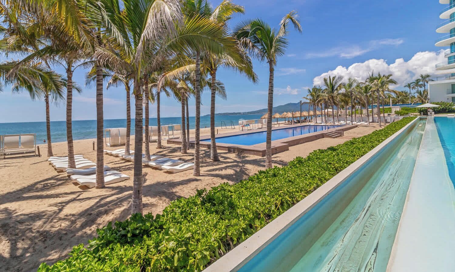 A resort with a pool, palm trees, and a beach area.