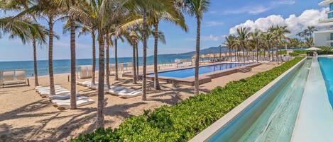Un complexe hôtelier doté d’une piscine, de palmiers et d’une plage.