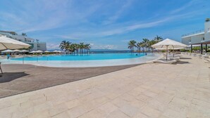 Ein Swimmingpool mit klarem, blauem Wasser, umgeben von Palmen und einer gefliesten Liegefläche.