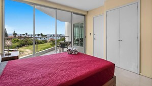 Ein Schlafzimmer mit einem großen Bett, einem Balkon mit Aussicht und einem Schiebetürenschrank.