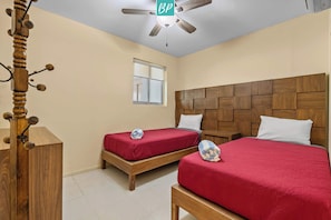 A hotel room with two beds, a wooden headboard, a ceiling fan, and a window. - Beachfront 2BR w/ Partial Ocean View + Resort Pools (Nuevo Nayarit)