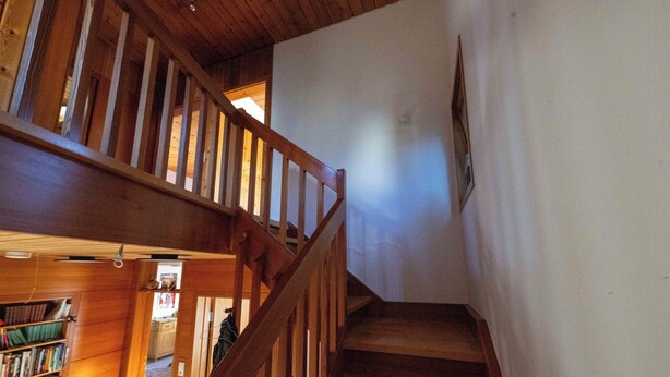 A wooden staircase leading to an upper floor, with a bookshelf and a door visible in the background. - 2 bedroom building in Hechingen with pool, balcony, terrace  for relaxing stay (Hechingen)