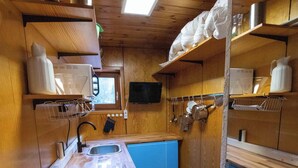A compact kitchen with wooden cabinets, a blue countertop, a sink, and a microwave. - 2 bedroom building in Hechingen with pool, balcony, terrace  for relaxing stay (Hechingen)