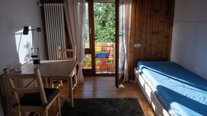 A small room with a bed, a table, and a chair. There is a window with curtains, and a view of the outside. - 2 bedroom building in Hechingen with pool, balcony, terrace  for relaxing stay (Hechingen)