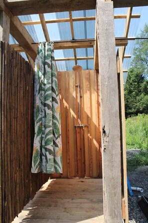 A wooden structure with a bamboo fence, a wooden door, and a patterned curtain.