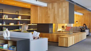 Ett modernt bibliotek med bokhyllor, en läshörna med soffor och en vägg med träpanel som ger ett stilfullt intryck.