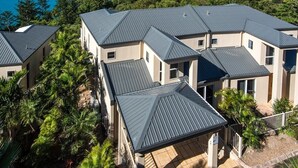 A cluster of modern houses with metal roofs, surrounded by lush greenery and a clear view of the sea. - La Bella Waters 5 and Free buggy - Hamilton Island (Hamilton Island)