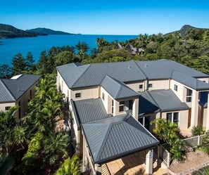 A cluster of modern houses with metal roofs, surrounded by lush greenery and a clear view of the sea. - La Bella Waters 5 and Free buggy - Hamilton Island (Hamilton Island)