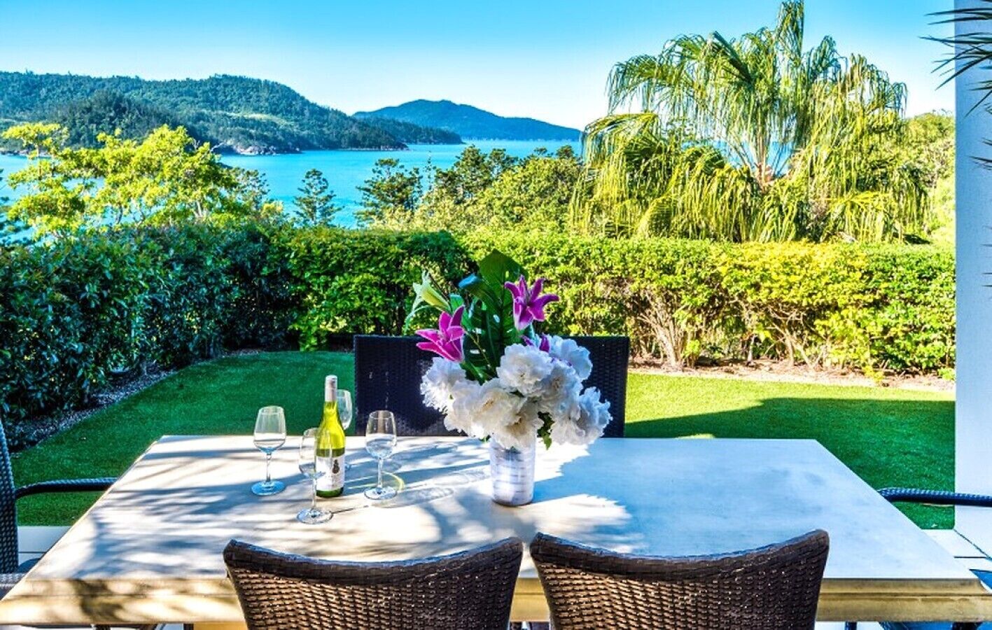 A table set for dining with a view of the sea and hills.