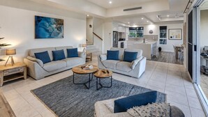 A modern living room with two sofas, a coffee table, and a rug. - La Bella Waters 5 and Free buggy - Hamilton Island (Hamilton Island)