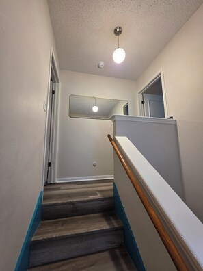 A staircase with wooden steps, white walls, and a blue trim. - Waterfront Canal Townhouse with Private Dock on the Island, Corpus Christi (Corpus Christi)