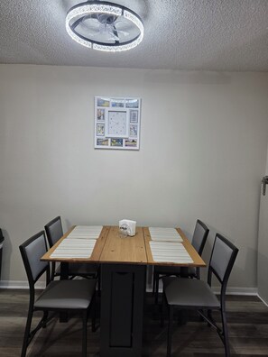 A conference room with a wooden table, six chairs, a clock with postage stamps, and a ceiling fan. - Waterfront Canal Townhouse with Private Dock on the Island, Corpus Christi (Corpus Christi)