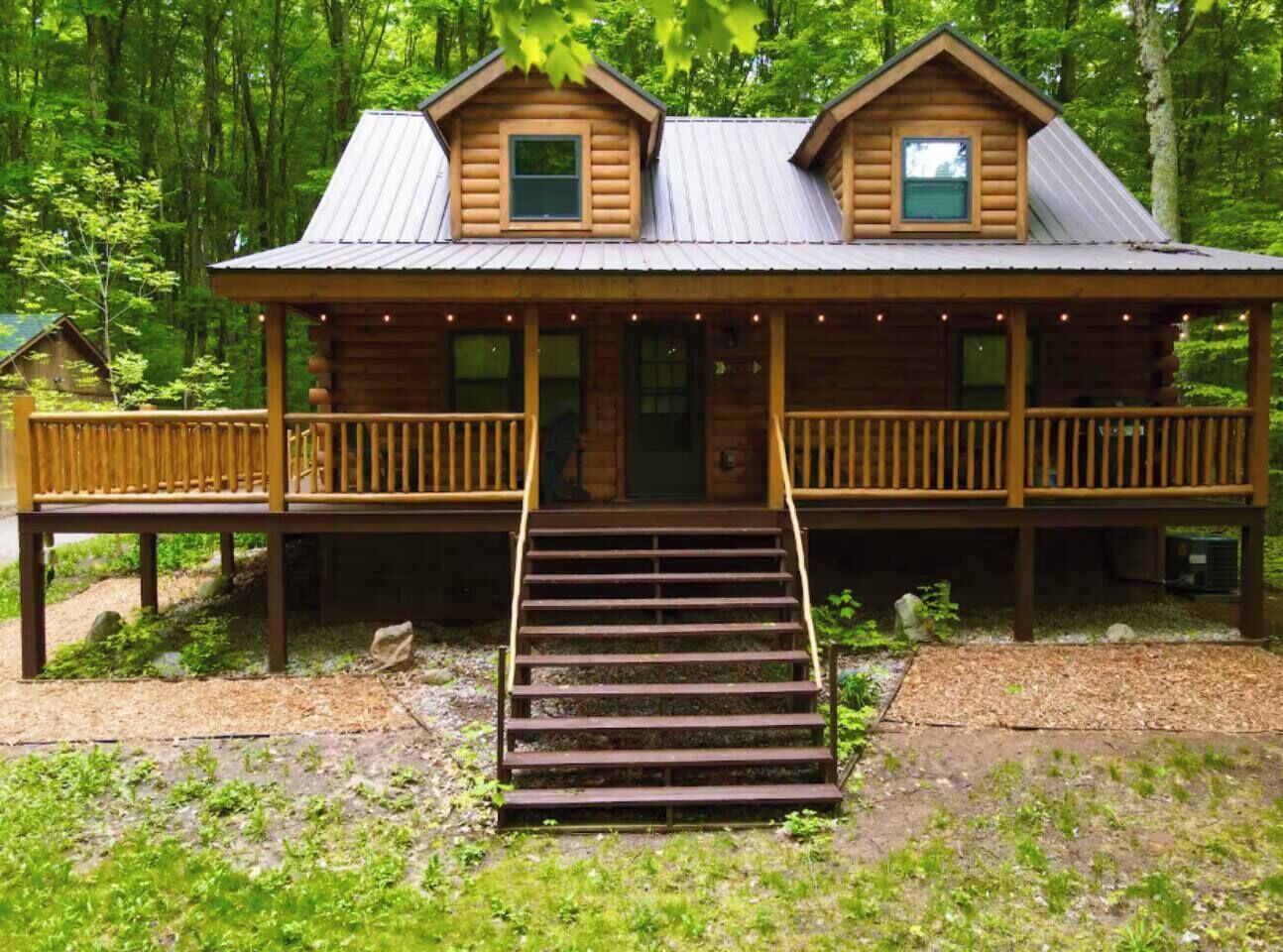 A wooden cabin with a porch and a staircase leading to the entrance.