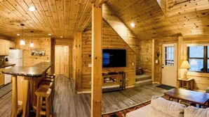 Interior de una cabaña de madera con cocina, comedor y sala de estar.