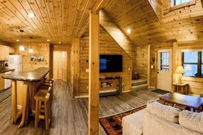 Ein Holzblockhaus-Interieur mit Küche, Essbereich und Wohnzimmer.