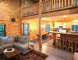 A cabin interior with a living area, dining space, and kitchen. - Log Cabin Sleeps 10 | Pool Pass | Golf + Ski (Bellaire)