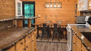 Un interior de madera con cocina, mesa de comedor, sillas y horno empotrado.