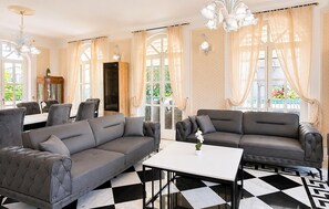 Eine Hotelhalle mit Schachbrettmuster-Boden, zwei grauen Sofas, einem weißen Tisch und einer Kronleuchter.